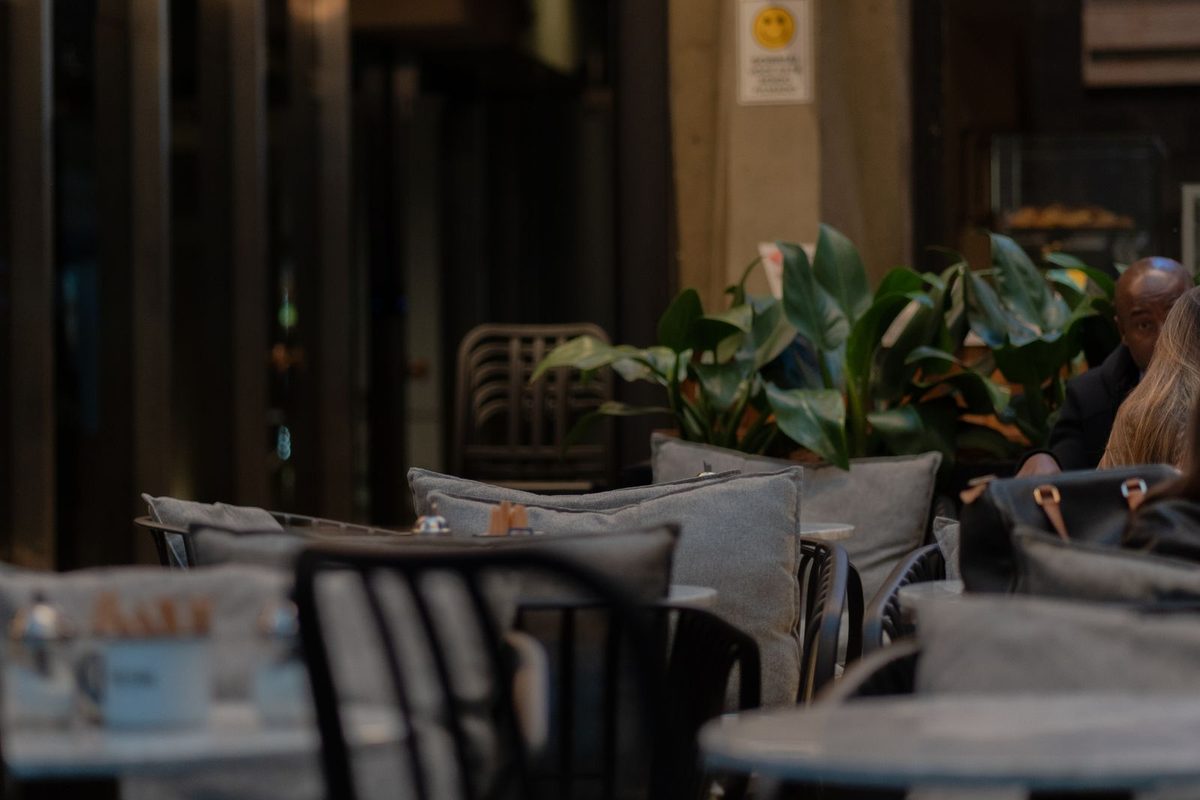Cosy cafe seating area with wooden tables, chairs and plants