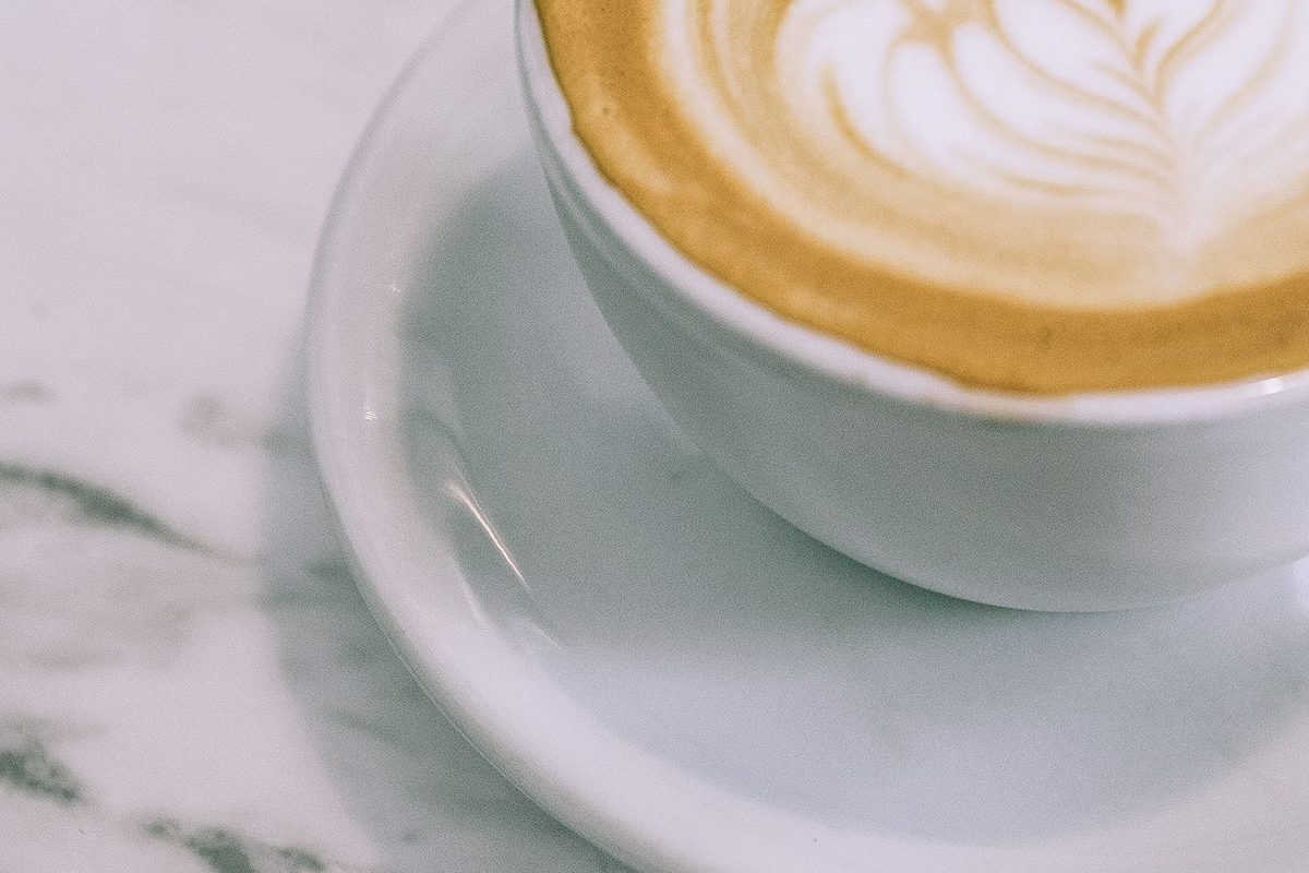 Cappuccino with latte art served on a marble cafe table