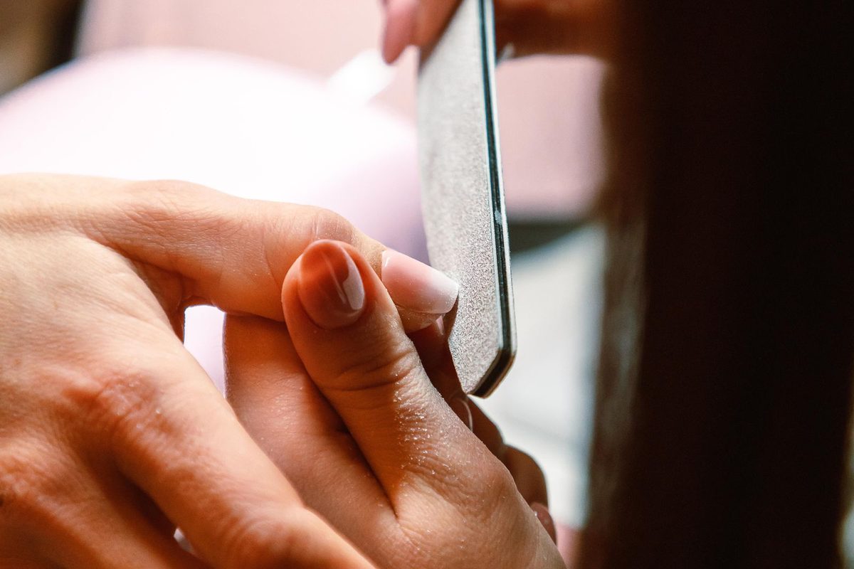 Manicurist applying nail treatment to a client's hands at a beauty salon