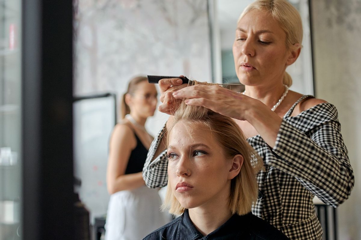 Hair stylist working on a client's hair at a salon mirror station