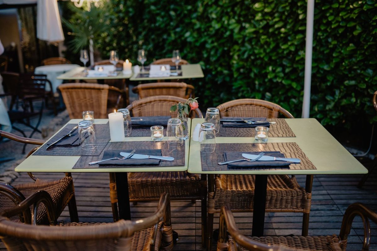 Restaurant terrace with wooden tables set for evening service under warm string lights