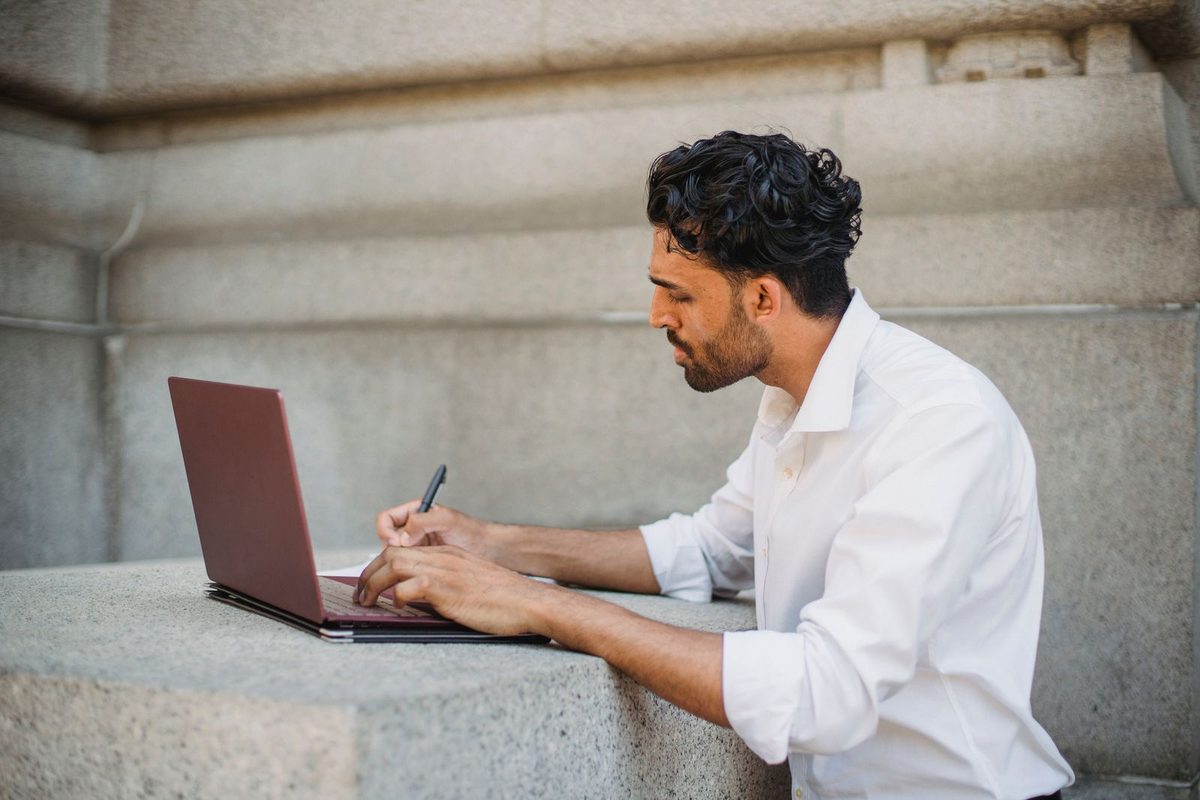 Small business owner working on their website at a laptop with a notebook